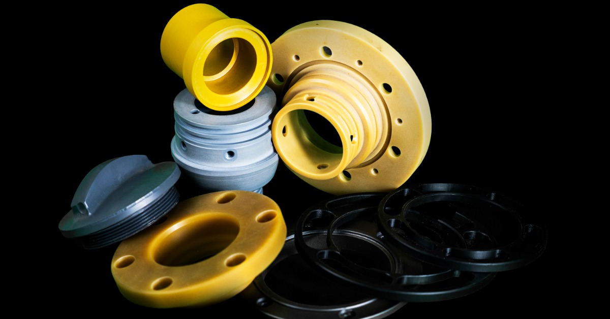 Yellow, blue, and black machined parts arranged together on a black surface with circular holes and threaded edges.